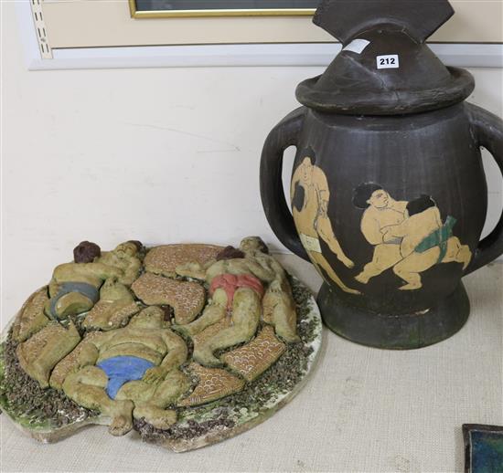 An Art pottery lidded jar decorated with sumo wrestlers and a wall plaque